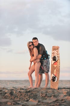 romantic couple in surf wear posing at beach on sunset at summer season