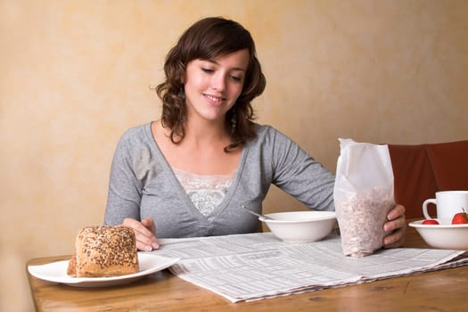 pretty young brunette having her morning breakfast while reading the newspaper