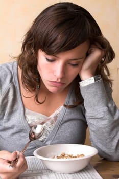 Pretty brunette reading the financial newspaper while eating her granola