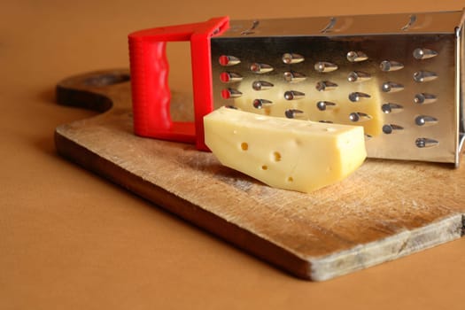 Piece of cheese on wooden cutting board near