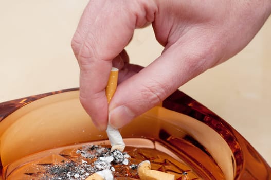 Detail of Males hand Stubbing Out Cigarette in Ashtray.