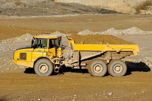A yellow dump truck is driving in mine