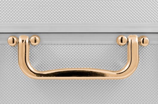 Golden handle detail of an aluminum case.
