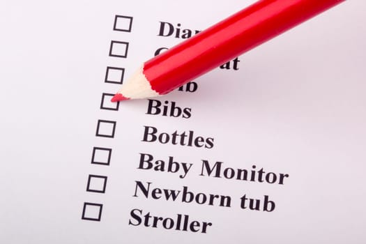 Red pencil marking a box on a checklist for a newborn.