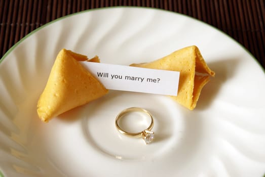 A marriage proposal using a fortune cookie and gold ring.