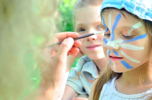 outdoor portrait of a child with his face being painted