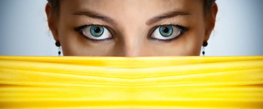 Closeup of beautiful female eyes behind the yellow silk