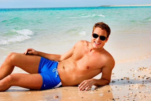Happy smiling man laying on the beach