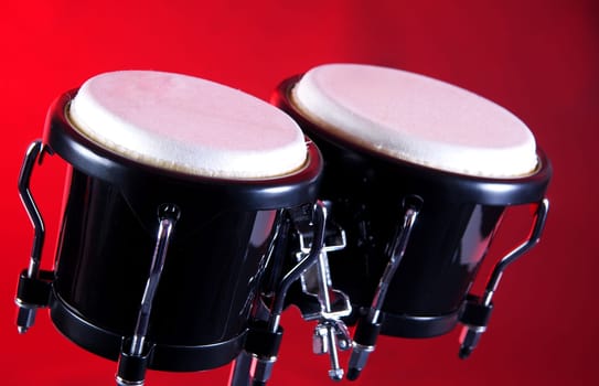 A set of black bongos isolated against a red background in the horizontal format with copy space.