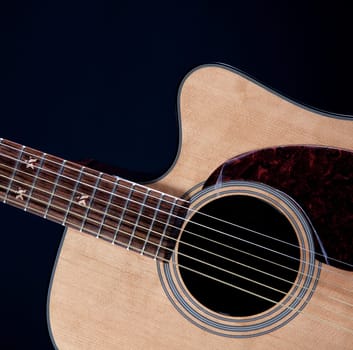 An acoustic guitar isolated against a black background in the square format.