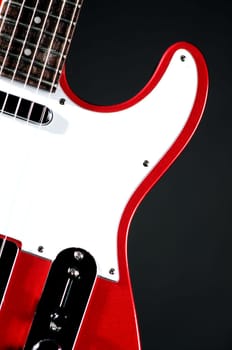An electric metallic red guitar isolated on a black background in the  vertical format with copy space.