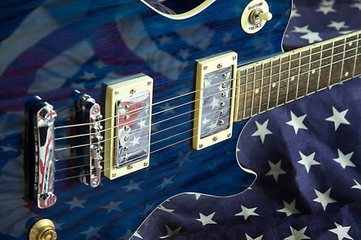 A blue wood electric guitar shot on an American flag background in the horizontal format.