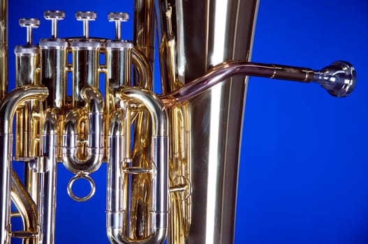 A gold brass bass tuba euphonium isolated on a blue background in the horizontal format with  copy space.