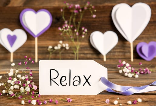 Label With English Text Relax. Purple And Lilac Decoration And Spring Flower Arrangement. Heart Symbols With Wooden Background.