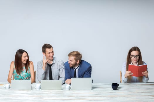 Business team working together at office on light gray background. all working on laptops. boss reading notebook. copyspace image