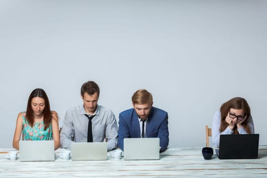 Business team working together at office on light gray background. all working on laptops. copyspace image