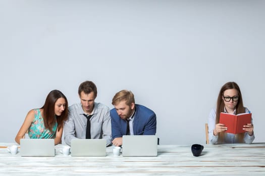 Business team working together at office on light gray background. all working on laptops. boss reading notebook. copyspace image