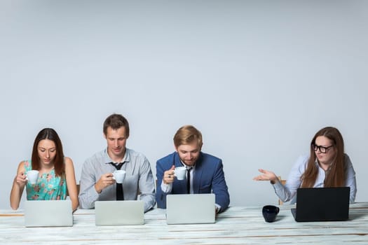 Business team working together at office on light gray background. boss is dissatisfied with the others drinking tea. copyspace image
