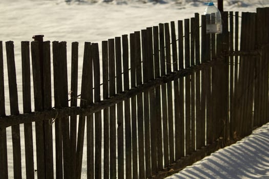 Fence made of wood in winter. Wooden fence in countryside. Territory of farm is in snow.