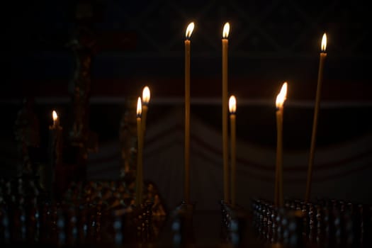 Candles in Church. Candles in Orthodox Church. Lights in dark. Religious rite. Candle flames.