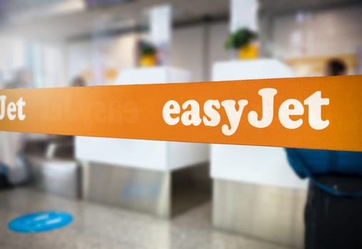 London, UK Jan 2023: Orange retractable belt barrier with the Easyjet logo inside an airport. Easyjet is a British multinational low-cost airline. Travel and airport security. Illustrative editorial