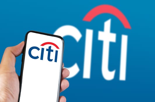 New York, US, March 2023: Hand holding a phone with Citi logo on the screen. Citi logo blurred on blue background. Citi is an American multinational investment bank. Illustrative editorial.