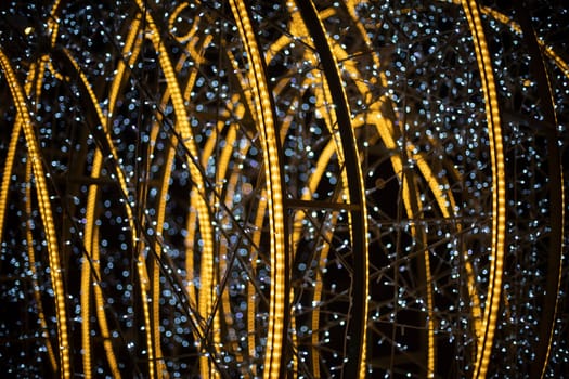 Luminous construction at night in city. Garlands in dark. Decoration of city for holiday. White and yellow LEDs.