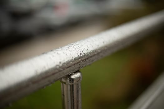 Wet handrail. Steel pipe in water droplets. Silver steel pole. Handrail.