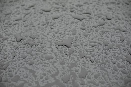 Raindrops on surface. Details of rain. Wet glass. Shades of gray in frame.