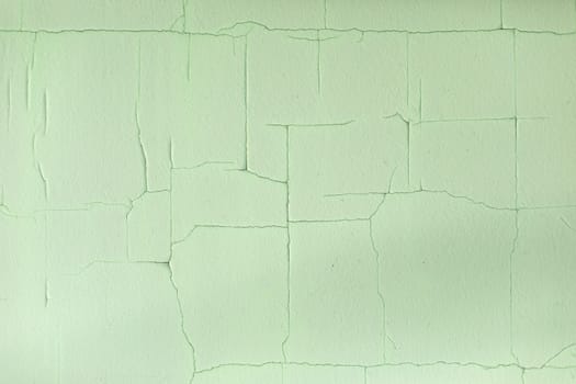 Cracks in paint. Old paint on wall. Fine mesh of cracks on surface. Green background.