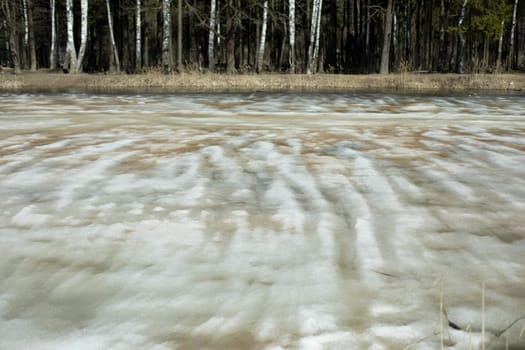 Ice is melting on lake. Spring Pond. Melted snow in forest. View of reservoir.