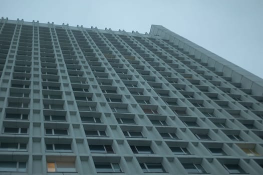 Lots of windows in skyscraper. High-rise building in city. Offices on grey day. Modern architecture of 20th century.
