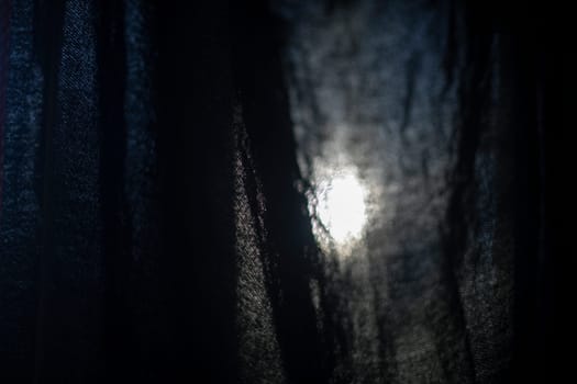 Light through fabric. Curtain on window. Black fabric texture on lumen. Fine mesh.