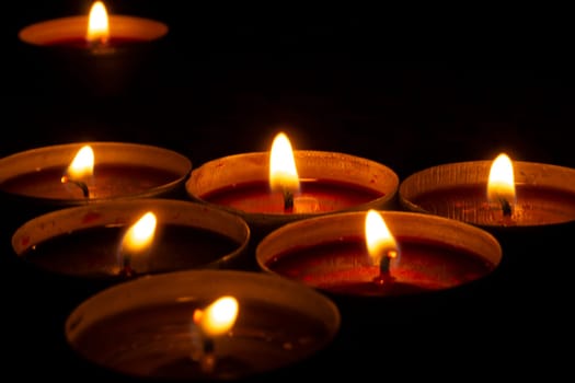 Candles burn in dark. Candle flames. Lights on black background. Hot wax.