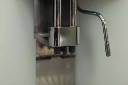 Coffee machine in detail. Coffee serving system. Supply of hot water jet for brewing drink. Chrome-plated parts of coffee machine.