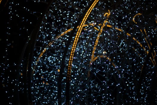 Luminous construction at night in city. Garlands in dark. Decoration of city for holiday. White and yellow LEDs.