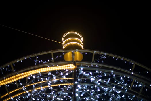 Garlands are arranged in arc. Urban decoration. Bright light bulbs. Garland construction.
