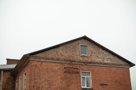 Old brick building. Brick house. Red wall. Ridge roof. 19th century industrial zone.