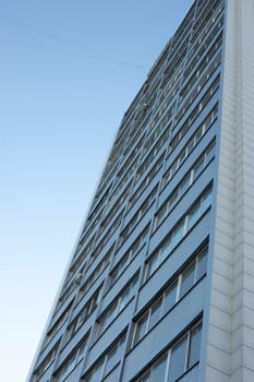 Grey building in city. High house. Windows in residential building. Modern architecture.