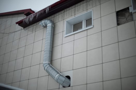 Pipe on building. Ventilation system. Building is tiled outside. Cooling in house.