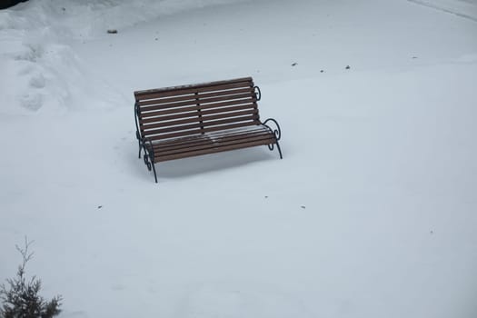 Bench in snow. Lonely shop in park in winter. Empty space. Details of park.