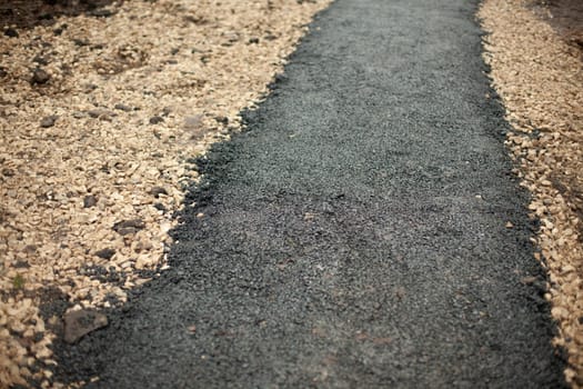 New asphalt. Construction of path in park. Details of road surface. Surface is black.