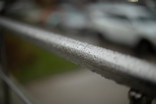 Wet handrail. Steel pipe in water droplets. Silver steel pole. Handrail.