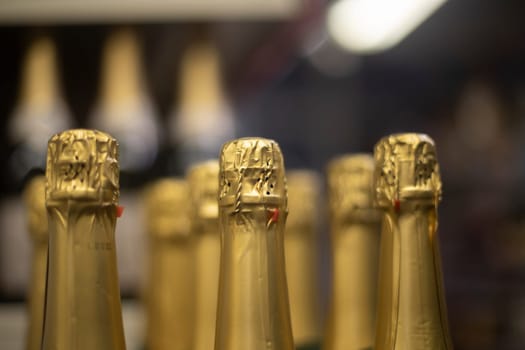 Champagne with gold foil. Bottles of wine in store. Alcoholic beverage stands in row. Bottle sales details.
