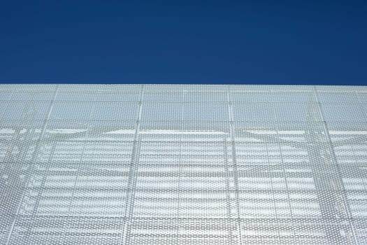 Grey building on sunny day. Wall without windows. Modern architecture. Steel frame of house.