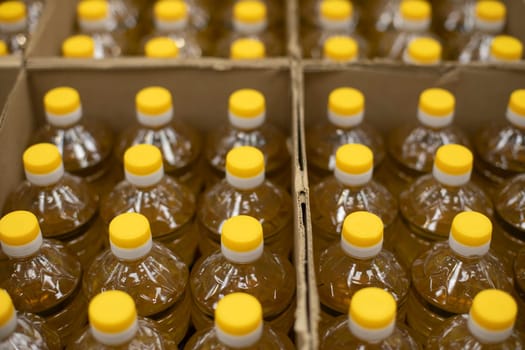 Yellow bottle caps. Sunflower oil in cardboard box. Goods in stock. Bottles stand in row.