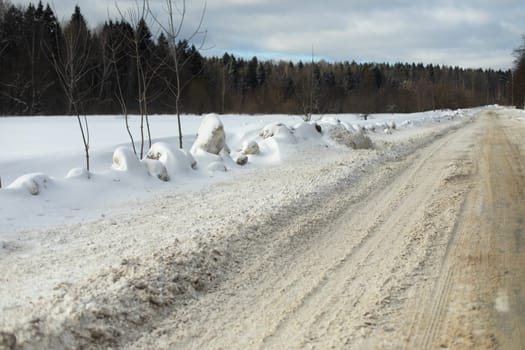 Road in winter in countryside. Snow in field. Roadside in snow. Empty track.
