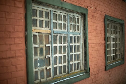 Old window in house. Details of 19th century architecture. Wooden lattice. Window frame. Brick building.