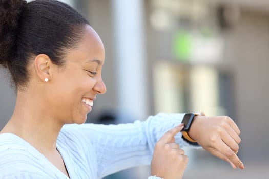 Profile of a happy black woman checking smartwatch in the street
