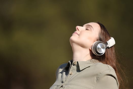 Woman meditating outside listening audio guide with headphone
